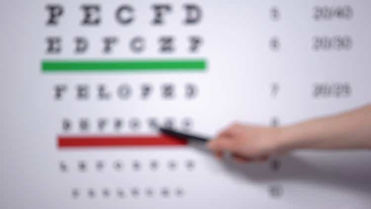 Ophthalmologist hand showing letter on eye chart to patient with vision problems