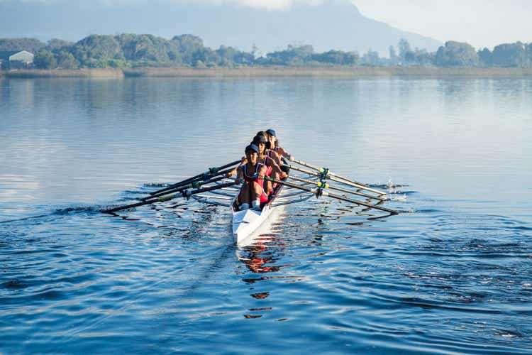Mixed race female rowing team training on a lake