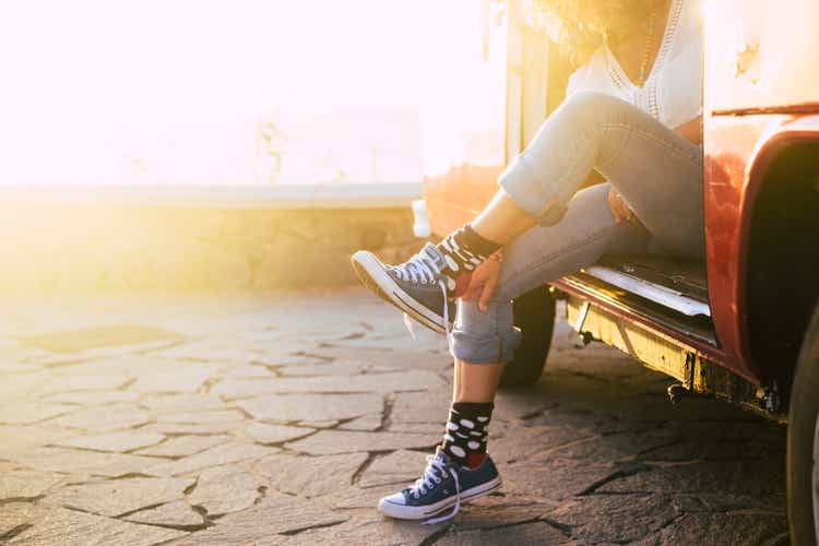 Travel concept for alternative vacation for people - woman with nice socks outside old vintage fur with sunlight on background - incomprehensible lady wearing sports shoes