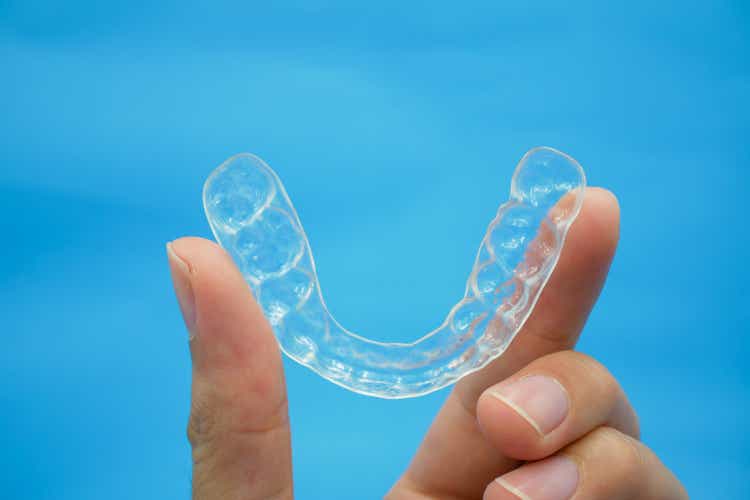 Hands on clear retainer teeth that isolated on blue background