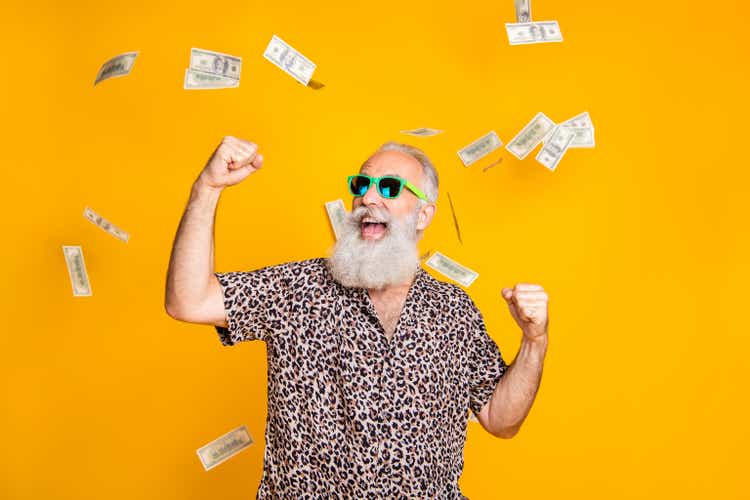 Portrait of crazy retired funky bearded old man with eyeglasses eyewear raise his fists scream yeah celebrate victory look at money falling wearing leopard shirt isolated over yellow background