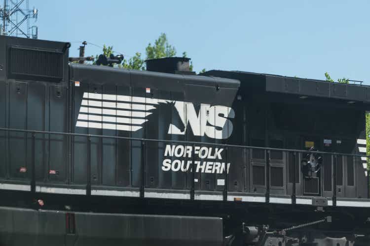 Norfolk Southern locomotive cargo freight train with cars passing on railroad tracks in Georgia downtown midtown city in summer
