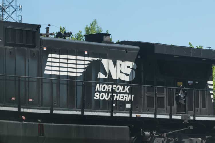 Norfolk Southern locomotive freight train with cars passing railroad tracks in central Georgia in summer