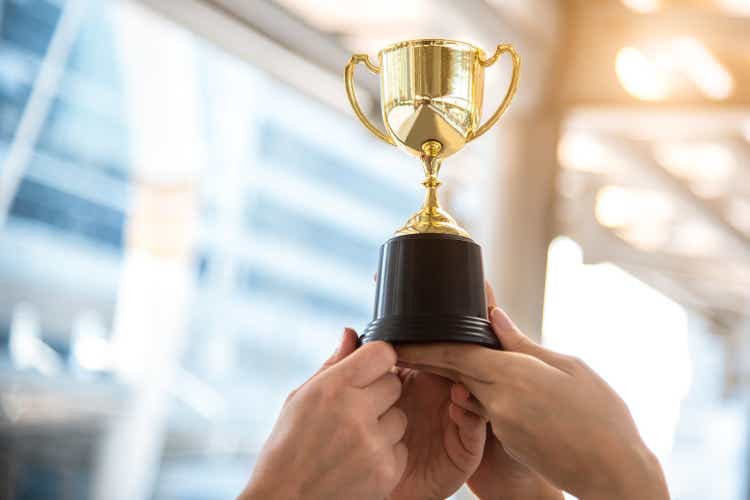 Champion golden trophy for winner with sport player hands in sport stadium background. Success and achievement concept. Sport and cup award theme. American football award and match game play prize