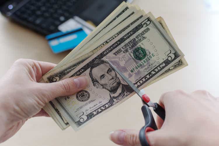 Cutting US Dollar banknote with a scissors.