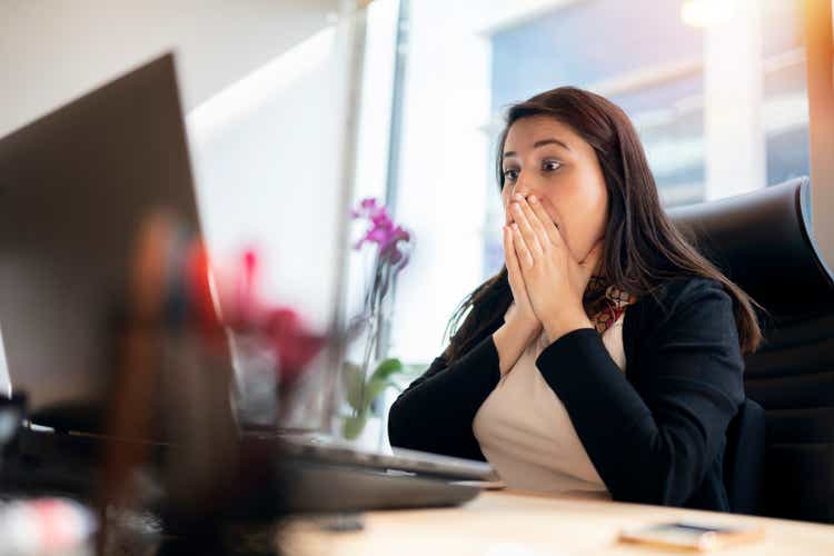 Shocked young woman looking at laptop screen