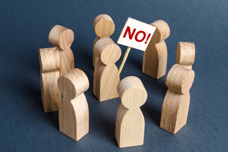 Person holding a NO poster surrounded by people. The concept of bullying and protest against. Disagreement and conviction for dissent. Strike Agitation and cooperation. Resistance and civil society.