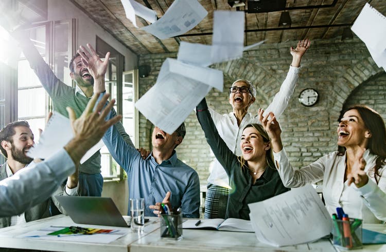 Group of playful entrepreneurs having fun while throwing paperwork in the office.