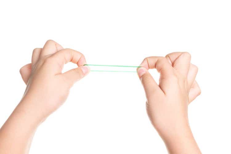 Child hand playing with elastic rubber band isolated on white