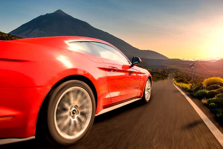 Auto sportiva rossa che corre ad alta velocità lungo la strada. Ford Mustang,strada a Tenerife