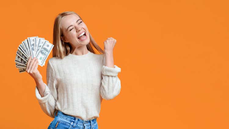 Joyful young girl holding bunch of money and rejoicing success