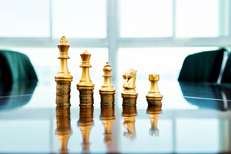 Chess pieces standing on the stacked coins