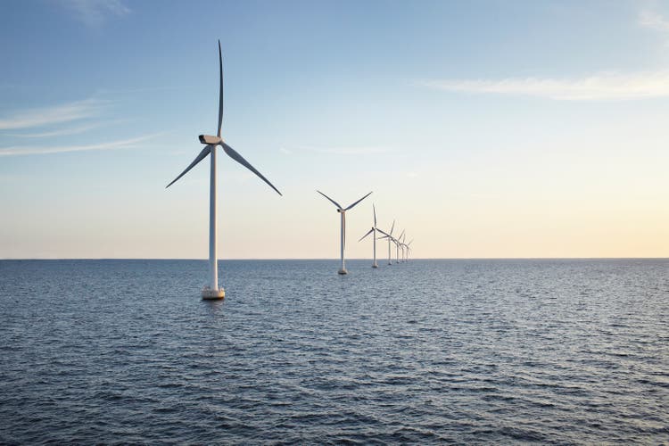 Row of winturbines in the sea shot in the sunset