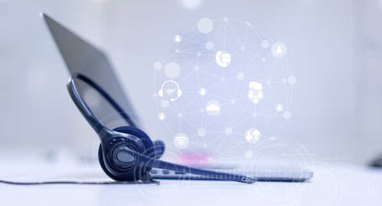 close up headset of call center and VOIP communication with futuristic virtual icon telecommunication technology on office table in monitoring room for network operation job concept
