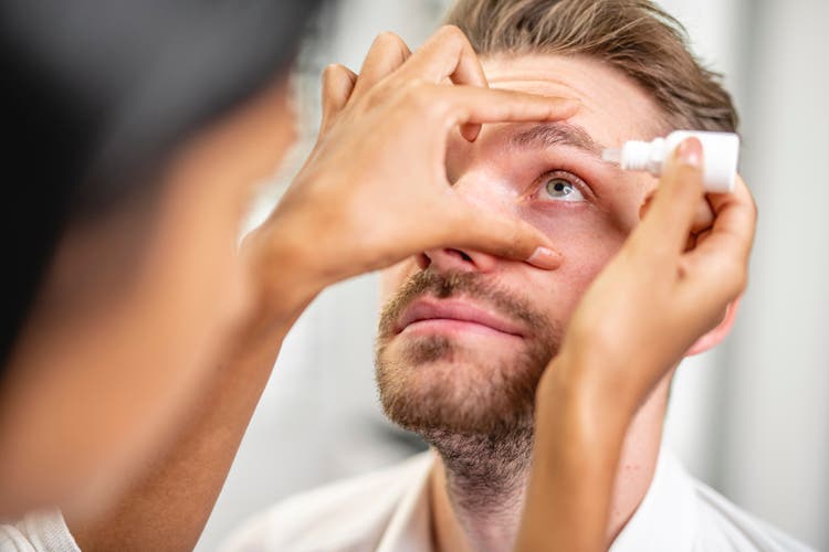 Caucasian mature man receiving eye drops at the doctor"s office