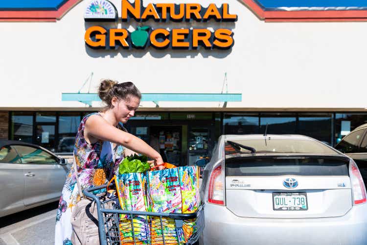 Woman with shopping cart and bags by Natural Grocers by Vitamin Cottage store in Durango, Colorado