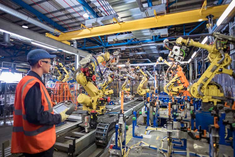 Apprentice engineer programming robots in car factory