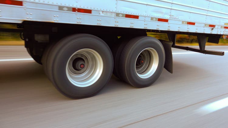 CLOSE UP: Freight semi truck passing by on highway, tires and wheels rolling