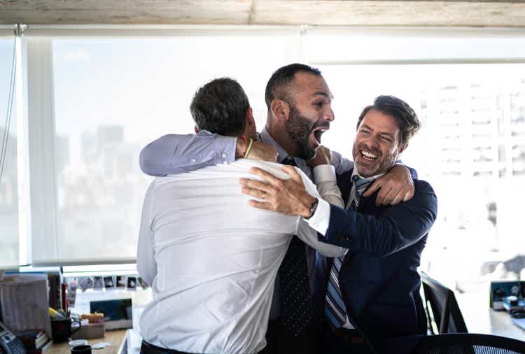 Excited group of coworkes embracing and jumping during a celebration