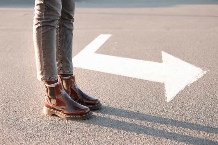 Feet standing beside a right turn sign.