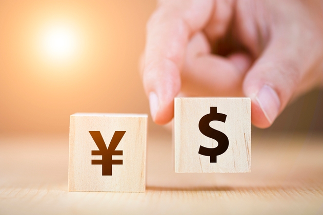 Hand putting wooden cube of US dollar sign to Yuan .US dollar is main and popular currency of exchange in the world.Investment and saving concept.