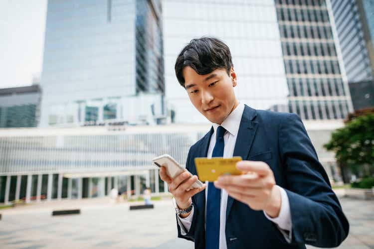Korean businessman using smart phone and credit card for online payment