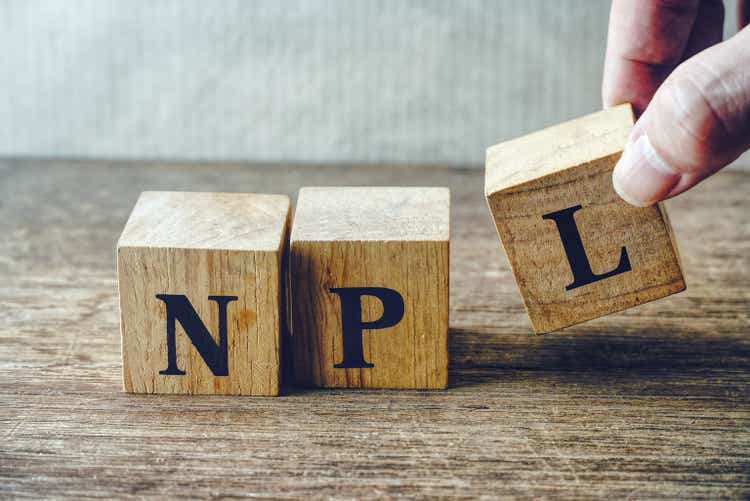 Hand pick up wood cube block which have text"NPL" , stock investment concept.