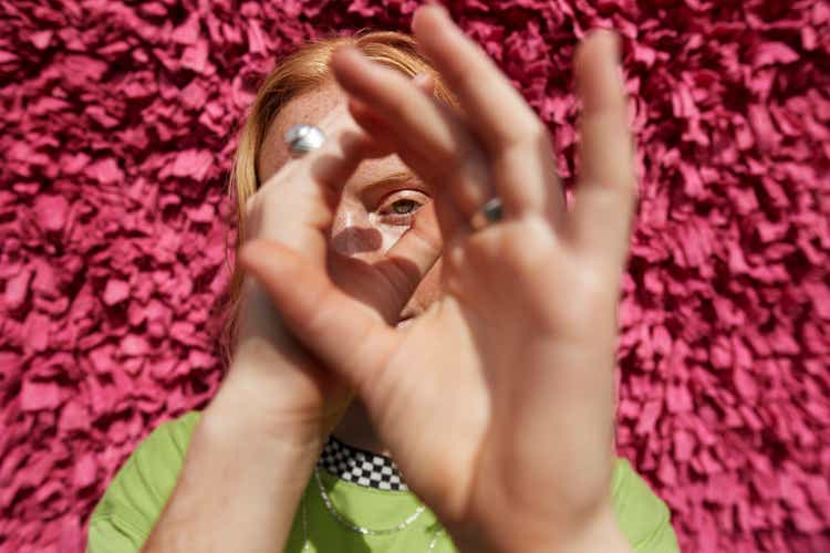 Beautiful woman gesturing against textured wall