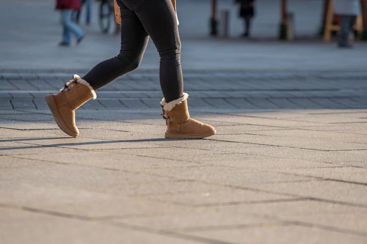 woman walks in ugg boots across a town´s market square