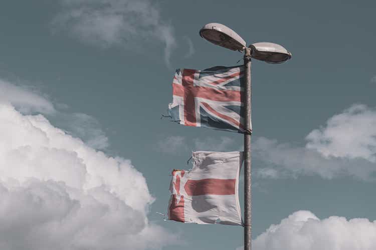 Tattered UK and Northern Ireland flags flying from a street light
