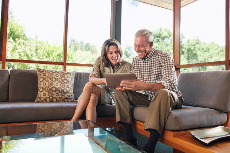 Mature couple sitting on sofa using digital tablet