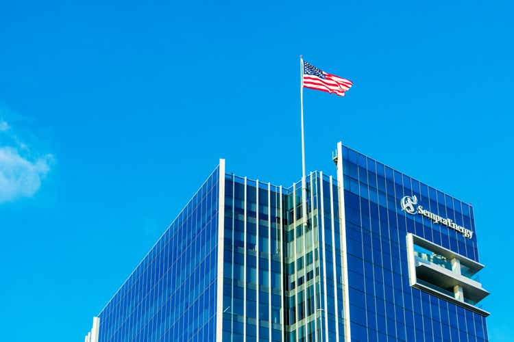 Sempra Energy corporate headquarters building facade. U.S. Flag proudly waving atop energy infrastructure company office under blue sky