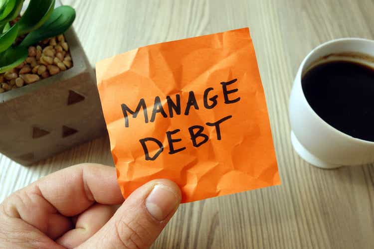 Manage debt - motivational reminder handwritten on sticky note