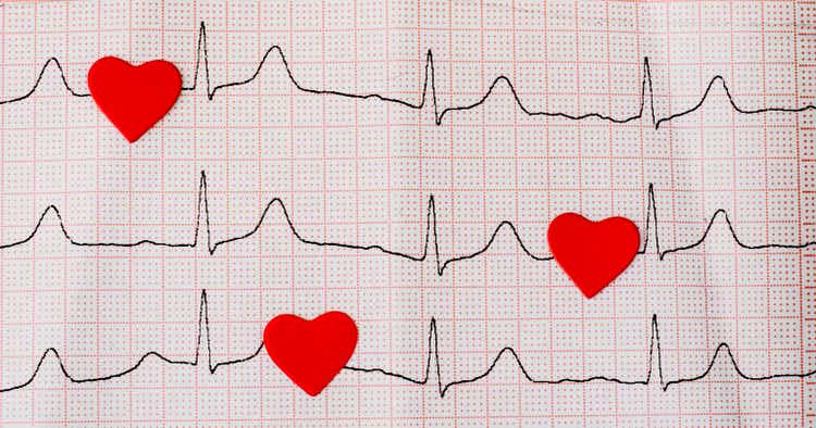 Red hearts on a cardiogram, a heartbeat symbol. Close up of an electrocardiogram in paper form. Healthcare and medical concept. Copy space