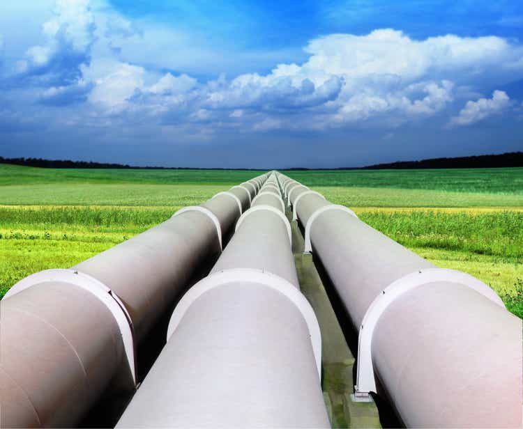 Three natural gas pipelines among green fields with blue sky