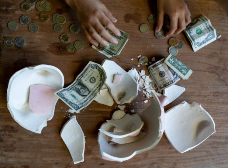 High angle view of unrecognizable person counting money after breaking a piggy bank