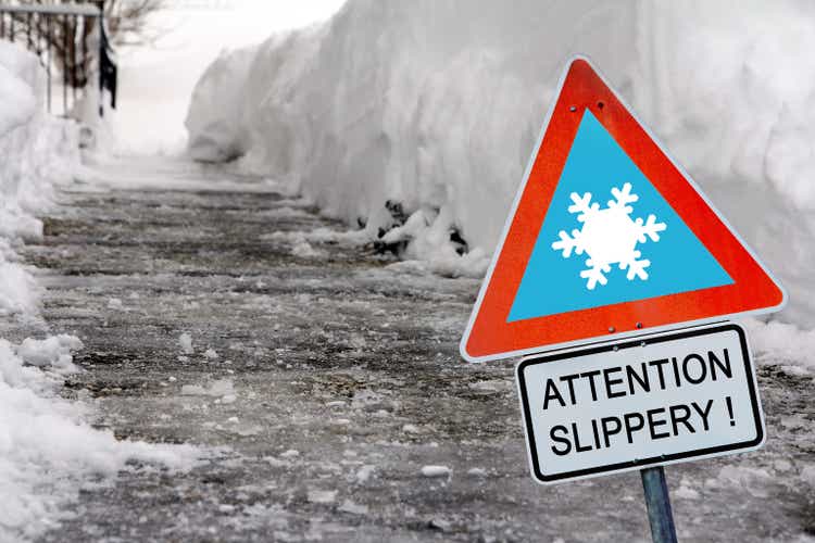 An icy road in winter with a sign Attention slippery!