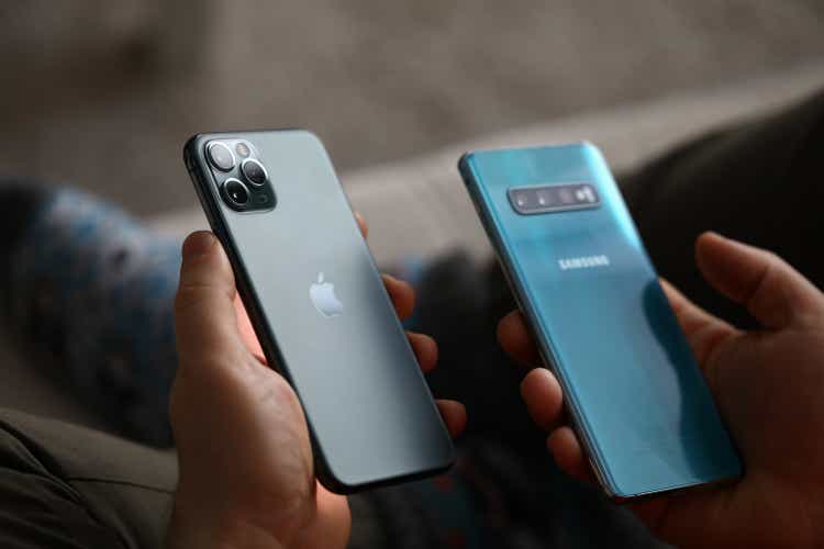 Male hand hold Apple iphone pro and samsung galaxy s 10