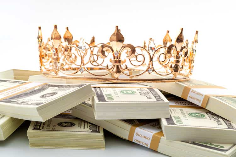 Cash is king, economic treasure and financially successful retirement conceptual idea with a golden metal crown on a pile of 100 dollar bills isolated on white background