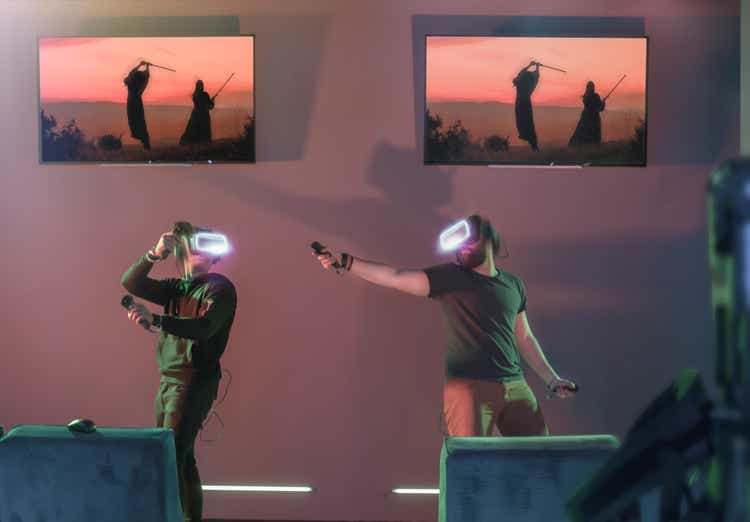 Gamers playing VR fighting game at futuristic visitor centre