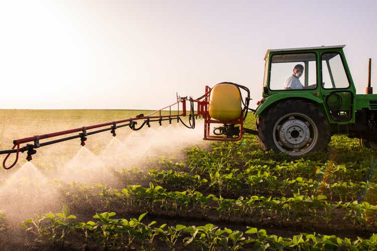 Tractor spraying pesticides on soy field with sprayer at spring