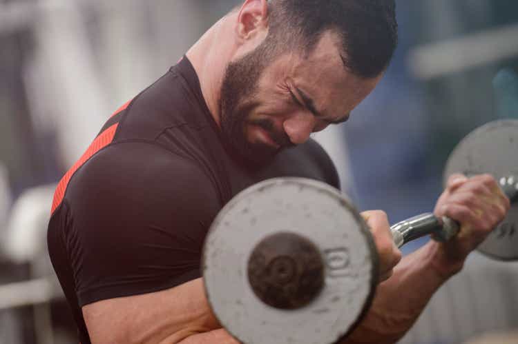 heavy painful lifting of iron barbell by young strong man with beard great mind motivation and concentration dedication with grimace of effort and pain on face