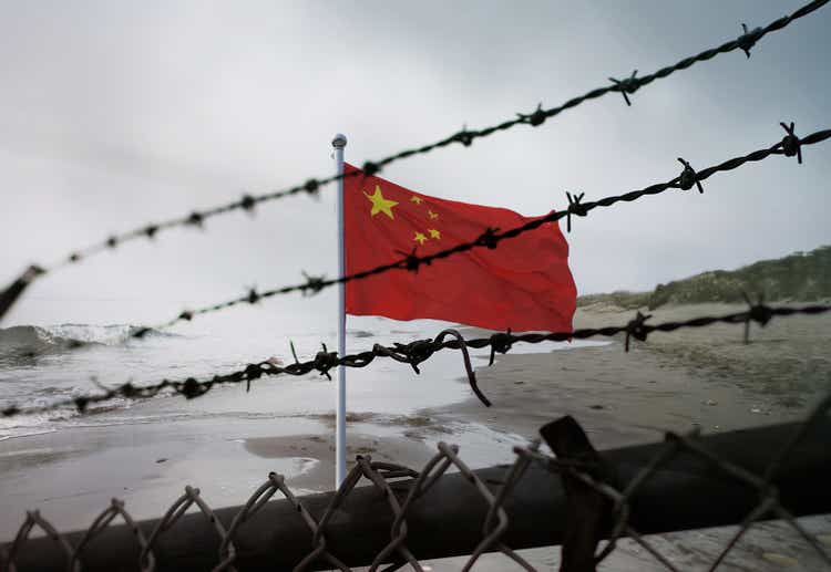 China border fence. Chinese flag behind a steel wire mesh