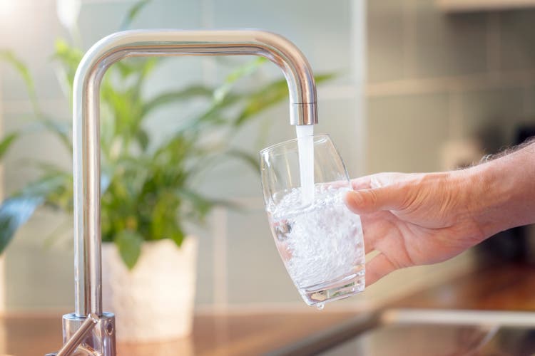 Llenar un vaso con agua potable del grifo de la cocina