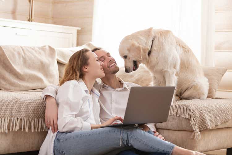 Young married couple using a laptop next to their beloved dog