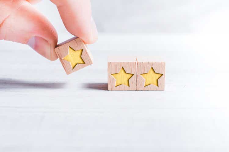 3-star ranking formed by wooden blocks and arranged by a male finger on a white table