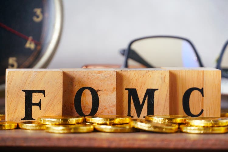 Wood cube which have text FOMC on working table and old clock on background,US economic data concept.