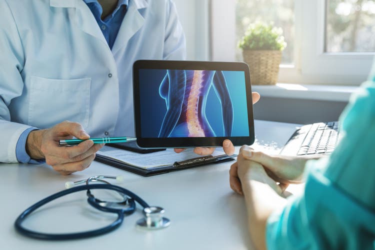 Arzt und Patient sprechen über Rückenschmerzbehandlung im Klinikbüro