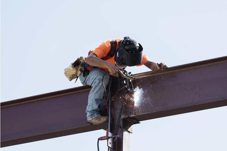 Hispanic ironworker welding a steel girder