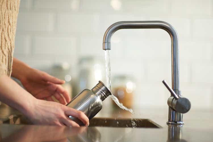 Cleaning a plastic free reusable water bottle in kitchen sink.